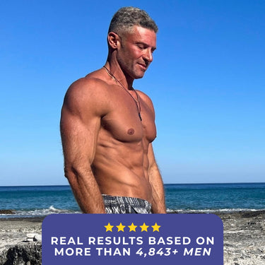 A muscular man standing on the beach with a serene ocean backdrop.